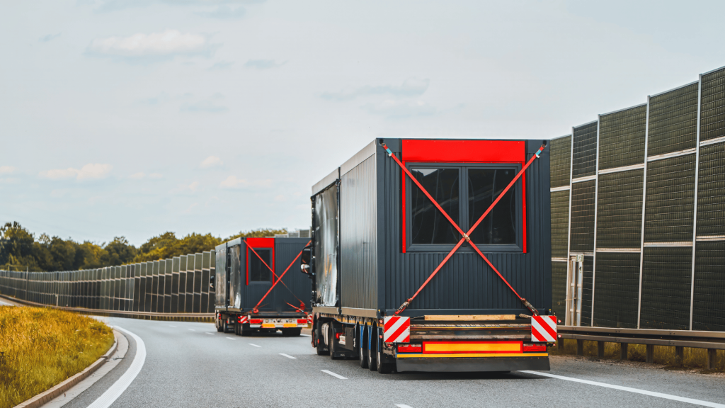 flatbed trucks carrying modular homes on an overcast day